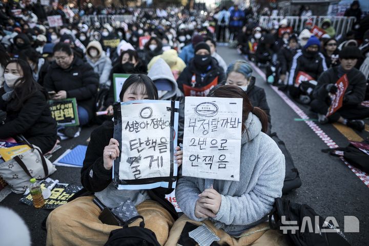 [서울=뉴시스] 정병혁 기자 = 14일 서울 영등포구 국회 앞에서 열린 '내란수괴 윤석열 즉각탄핵' 범국민 촛불대행진에 참가한 시민들이 피켓을 들고 있다. 2024.12.14. jhope@newsis.com