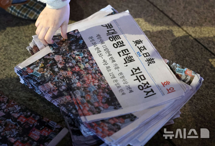 [서울=뉴시스] 홍효식 기자 = 윤석열 대통령에 대한 탄핵소추안 재표결이 가결된 14일 오후 서울 종로구 광화문역 일대에 한 시민이 윤 대통령 탄핵 가결 관련 호외를 가져가고 있다. 2024.12.14. yesphoto@newsis.com