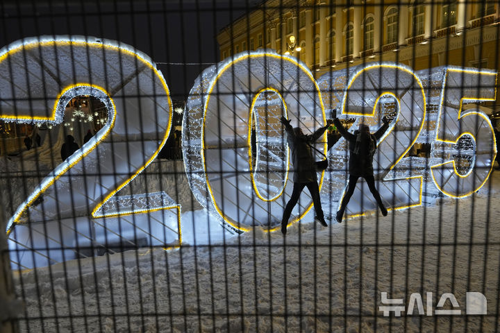 [상트페테르부르크=AP/뉴시스] 15일(현지시각) 크리스마스와 새해를 앞두고 러시아 상트페테르부르크에 열린 크리스마스 마켓에서 두 소녀가 '2025' 조형물을 배경으로 점프 샷을 찍고 있다. 2024.12.16.