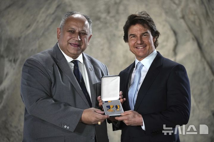 Tom Cruise, right, receives a Navy Distinguished Public Service Award from The United States Secretary of the Navy Carlos Del Toro presents at the Longcross South Studios, in Runnymede, Surrey, England, Tuesday, Dec. 17, 2024. (AP Photo/Kin Cheung)