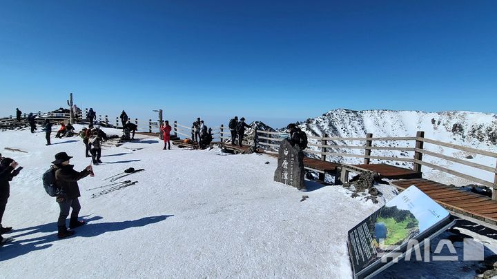 [제주=뉴시스] 한라산 백록담 정상에 도착한 탐방객들이 표지석 앞에서 기념사진을 찍으며 정상등산을 인증하고 있다. (사진=뉴시스DB) photo@newsis.com
