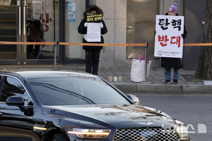 [서울=뉴시스] 최동준 기자 = 지난달 18일 서울 종로구 헌법재판소 앞에서 각각 탄핵 찬성과 반대를 촉구하는 1인 시위자 앞으로 헌법재판관 차량이 들어가고 있다. 2025.01.13. photocdj@newsis.com