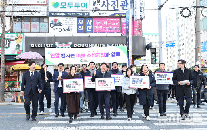 [창원=뉴시스]박완수(앞줄 가운데) 경남도지사가 19일 창원특례시 의창구 팔룡동 인근에서 기업인, 노동자, 도청 공무원 등과 함께 송년회, 가족 외식 등 연말연시 계획 정상 추진을 권하는 소비 진작 대도민 캠페인 동참을 호소하고 있다.(사진=경남도 제공) 2024.12.19. photo@newsis.com