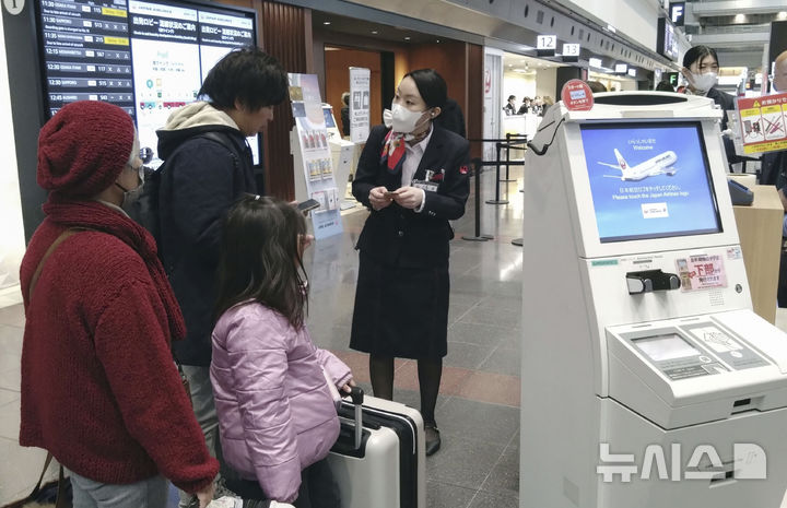 [도쿄=AP/뉴시스] 26일(현지시각) 일본 도쿄의 하네다 국제공항에서 일본항공(JAL) 직원이 승객들의 항공기 탑승을 돕고 있다. JAL은 이날 오전 자사 네트워크가 사이버 공격을 받아 소화물 관리 시스템에 장애가 발생, 일부 노선 출발이 지연됐다고 밝혔다. 2024.12.26.