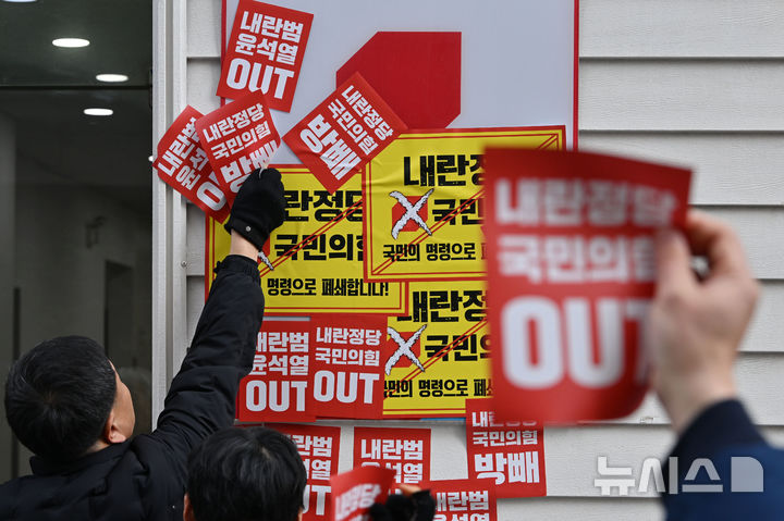 [광주=뉴시스] 이영주 기자 = 윤석열정권 즉각퇴진·사회대개혁 광주비상행동이 27일 오전 광주 서구 치평동 국민의힘 광주시당사 앞에서 국민의힘 해체 촉구 기자회견을 열어 당사가 입주한 건물에 항의성 스티커를 붙이고 있다. 2024.12.27. leeyj2578@newsis.com