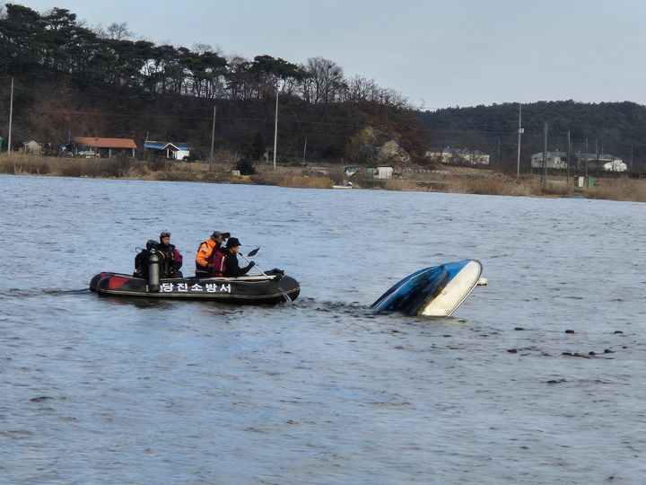 [당진=뉴시스] 28일 낮 12시14분께 충남 당진시 대호지면 적서리 대호저수지에서 어장을 하던 배가 뒤집힌 채 발견돼 고무보트를 타고 출동한 소방대원들이 주변을 수색하고 있다. (사진=당진소방서 제공) 2024.12.28. photo@newsis.com *재판매 및 DB 금지