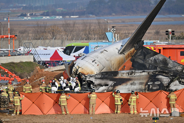 [무안=뉴시스] 이영주 기자 = 제주항공 소속 여객기 착륙 도중 충돌 사고가 발생한 29일 오후 전남 무안국제공항 사고현장 주변에서 소방 당국이 숨진 탑승객들을 수습하고 있다. 2024.12.29. leeyj2578@newsis.com