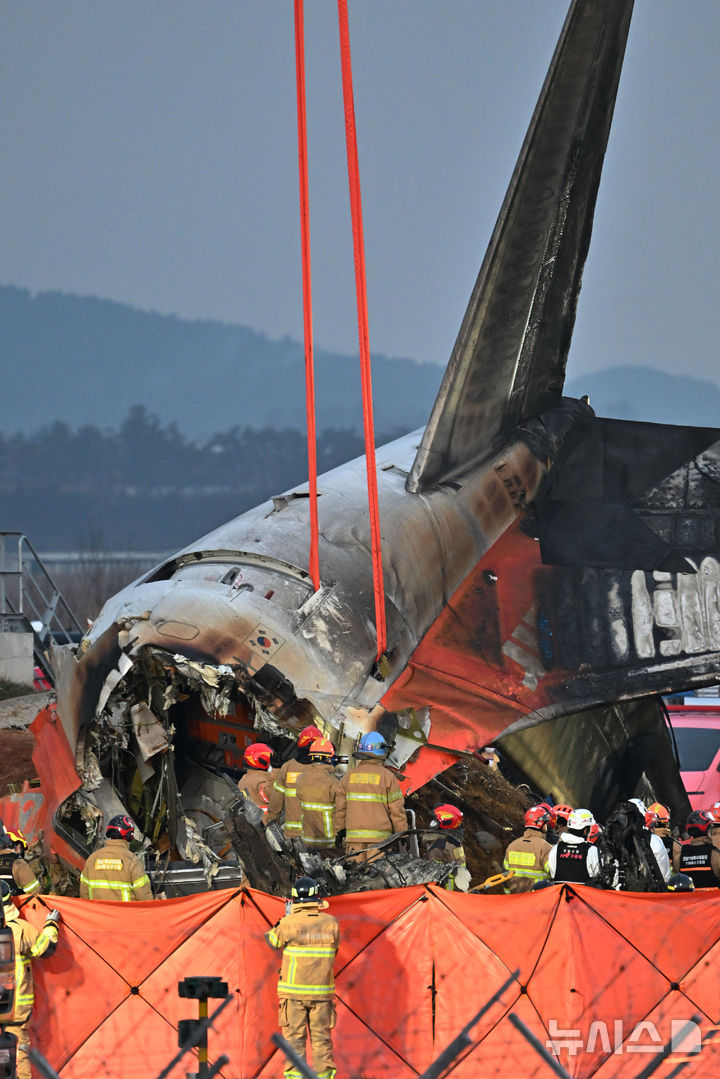 [무안=뉴시스] 이영주 기자 = 제주항공 소속 여객기 착륙 도중 충돌 사고가 발생한 29일 오후 전남 무안국제공항 사고현장에서 소방 당국이 사고 여객기 꼬리날개를 들어 올리며 수습 작업을 벌이고 있다. 2024.12.29. leeyj2578@newsis.com