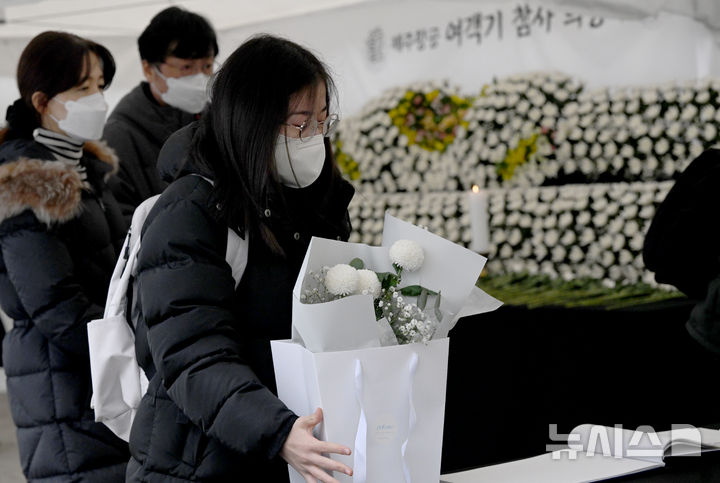 [광주=뉴시스] 김혜인 기자 = 제주항공 여객기 충돌 참사 발생 이튿날인 30일 오전 광주 동구 5·18민주광장 분향소에서 희생자의 친구가 헌화 꽃다발을 들고 분향소에 들어서고 있다. 2024.12.30. hyein0342@newsis.com