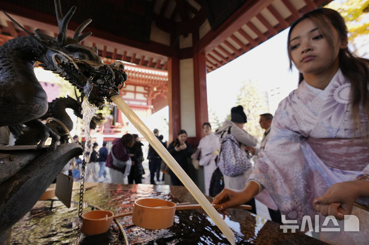 [도쿄=AP/뉴시스] 지난해 12월 31일(현지 시간) 일본 도쿄 센소지 사찰에서 한 호주 관광객이 본당 입장 전 손을 씻어 정화 의식을 치르고 있다. 2025.10.15.