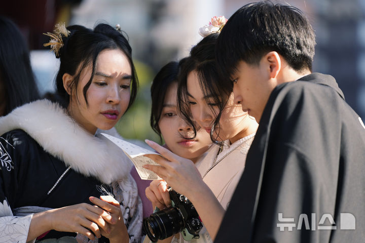 [도쿄=AP/뉴시스] 지난해 12월 31일(현지 시간) 일본 도쿄 센소지 사찰에서 베트남 관광객들이 새해를 앞두고 새해 운세가 적힌 '오미쿠지'를 확인하고 있다. 2025.11.19.