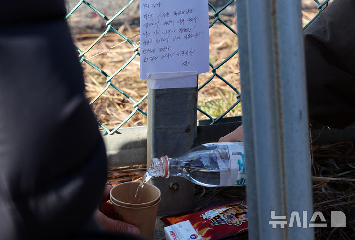 [무안=뉴시스] 이영환 기자 = 31일 오전 전남 무안국제공항 제주항공 여객기 충돌 사고 현장을 찾은 조문객들이 술을 따르고 있다. 2024.12.31. 20hwan@newsis.com