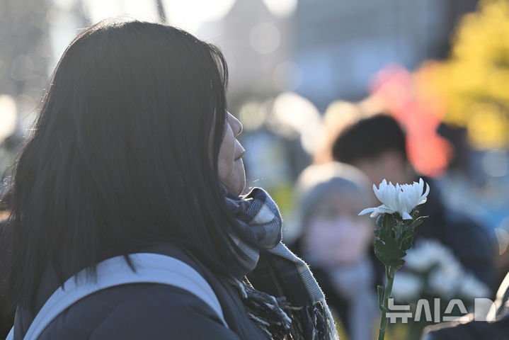 [광주=뉴시스] 이영주 기자 =  2024년 한 해 마지막 날이자 제주항공 여객기 참사 사흘째 되는 날인 31일 오후 광주 동구 5·18민주광장에 마련된 합동분향소에서 한 시민이 국화꽃을 든 채 입술을 깨물고 있다. 2024.12.31. leeyj2578@newsis.com