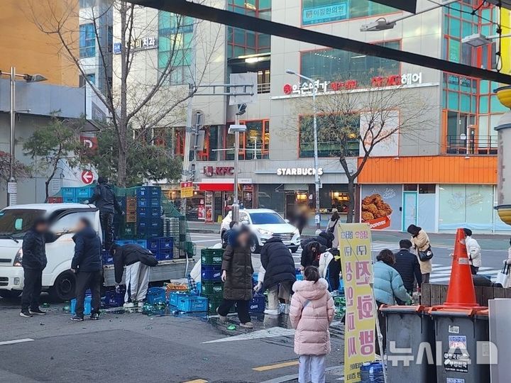 [고양=뉴시스] 도로에 쏟아진 소주병 치우는 시민들. (사진=독자 제공) 2025.01.03 photo@newsis.com