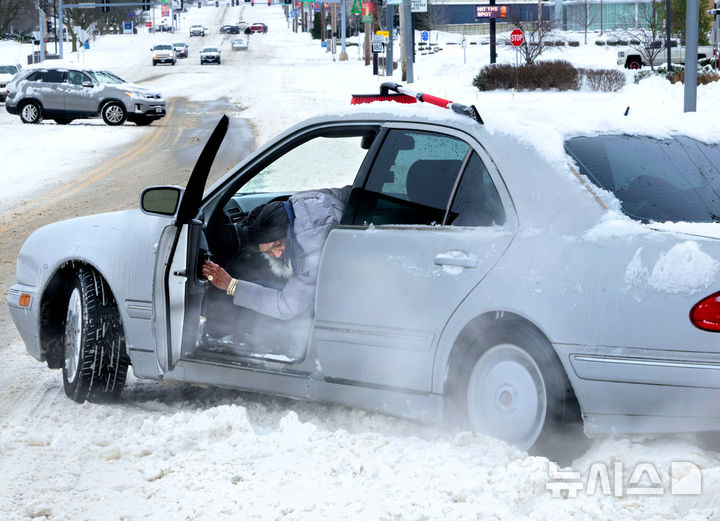 [세인트앤=AP/뉴시스] 미 미주리주 세인트앤의 한 주민이 지난 1월 6일 눈 때문에 도로에서 바퀴가 헛도는 차량을 빼내려 하고 있다.미 중·동부에 내린 폭설로 정전과 교통마비 등 피해가 잇따르고 2월 22일 부터 뉴욕 등 일부지역 통행금지도 실시된다. 2026.02.23.
