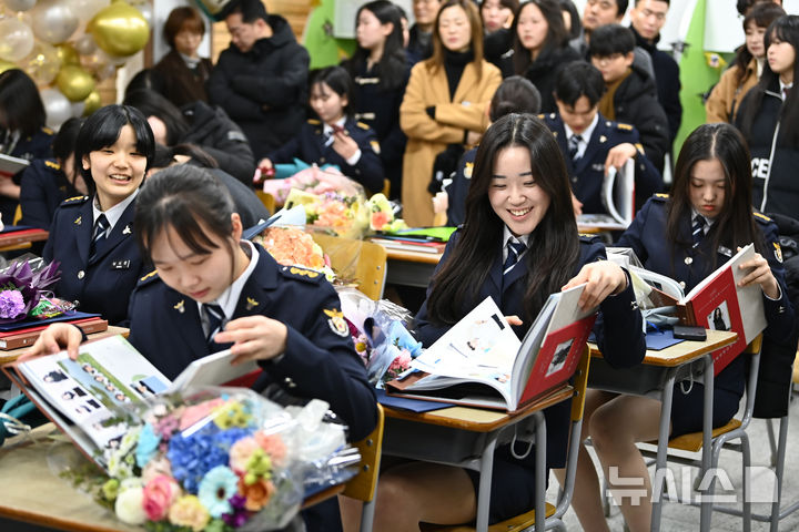 [수원=뉴시스] 김종택 기자 = 8일 경기도 수원시 삼일공업고등학교에서 열린 졸업식에서 경찰사무행정과 졸업생들이 졸업 앨범을 살펴보고 있다. 2025.01.08. jtk@newsis.com