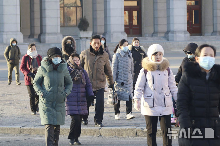 [평양=AP/뉴시스] 9일과 10일 북한 평양에 강풍과 한파 경보가 발효된 가운데 9일 방한복을 챙겨 입은 평양 시민들이 중앙구역 도로를 건너고 있다. 2025.01.09.