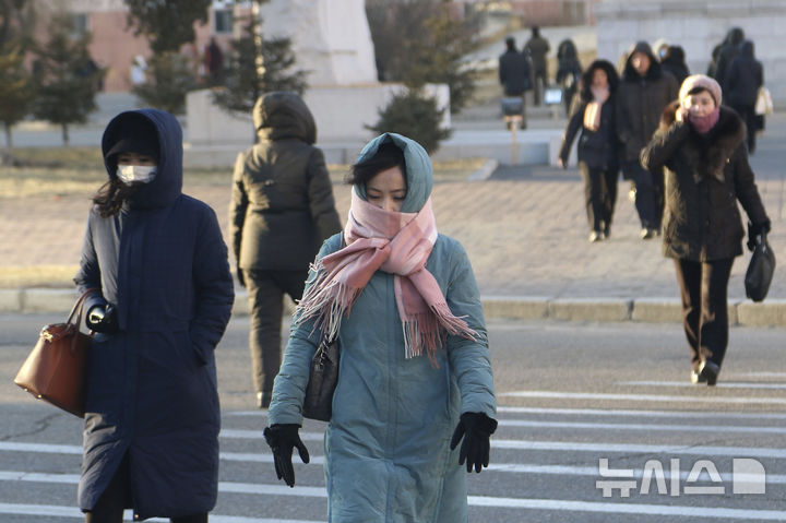 [평양=AP/뉴시스] 9일과 10일 북한 평양에 강풍과 한파 경보가 발효된 가운데 9일 방한복을 챙겨 입은 평양 시민들이 중앙구역 도로를 건너고 있다. 2025.01.09.