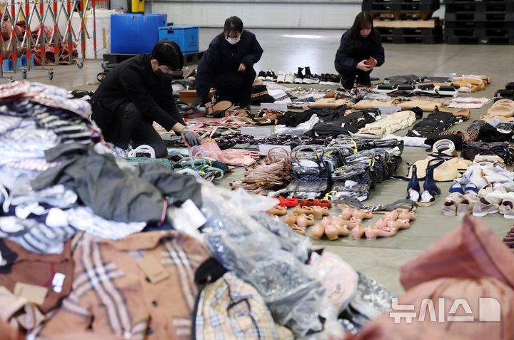 [부산=뉴시스] 하경민 기자 = 부산세관 직원들이 9일 부산 강서구 부산세관신항지정장치장에서 유통업자로부터 압수한 중국산 짝퉁 제품들을 정리하고 있다.  부산세관은 중국서 가방, 의류 등 시가 200억원 상당의 짝퉁 제품 1만여 점을 제작해 특송화물로 밀반입한 뒤 주택가 인근 원룸에 보관하며 온라인 쇼핑몰을 통해 판매한 전자상거래업체 대표 A(40대·여)씨를 관세법, 상표법, 범죄수익은닉의규제및처벌등에관한법률 위반 등의 혐의로 검찰에 불구속 송치했다고 밝혔다. 2025.01.09. yulnetphoto@newsis.com