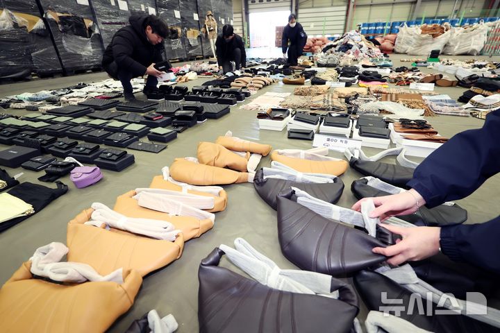 [부산=뉴시스] 하경민 기자 = 부산세관 직원들이 9일 부산 강서구 부산세관신항지정장치장에서 유통업자로부터 압수한 중국산 짝퉁 제품들을 정리하고 있다.  부산세관은 중국서 가방, 의류 등 시가 200억원 상당의 짝퉁 제품 1만여 점을 제작해 특송화물로 밀반입한 뒤 주택가 인근 원룸에 보관하며 온라인 쇼핑몰을 통해 판매한 전자상거래업체 대표 A(40대·여)씨를 관세법, 상표법, 범죄수익은닉의규제및처벌등에관한법률 위반 등의 혐의로 검찰에 불구속 송치했다고 밝혔다. 2025.01.09. yulnetphoto@newsis.com