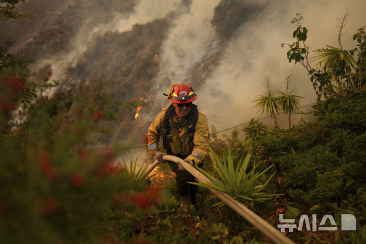 [로스앤젤레스=AP/뉴시스] 11일(현지 시간) 미국 캘리포니아주 로스앤젤레스 맨더빌 캐니언에서 팰리세이즈 화재가 발생해 소방대원이 화재 진압을 하고 있다. 2025.01.13.