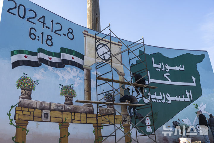 [이드리브=AP/뉴시스] 1월13일(현지 시간) 시리아 이드리브 시내 광장에서 자원봉사자들이 '승리의 벽화'를 그리고 있다. 벽화에는 바샤르 아사드 정권이 몰락한 일시와 "시리아는 모든 시리아인의 것"이라는 글귀가 적혀있다. 2025.03.11.