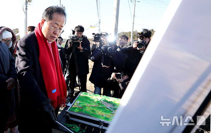 [대구=뉴시스] 이무열 기자 = 홍준표 대구시장이 15일 대구 군위군 소보면 내의리 대구경북신공항 사업부지를 찾아 위치도 현황판을 살펴보고 있다. 2025.01.15. lmy@newsis.com