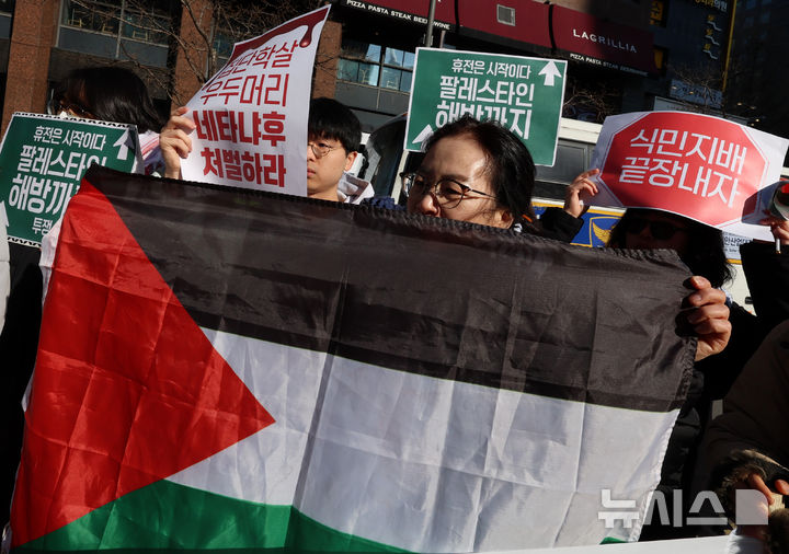 [서울=뉴시스] 이영환 기자 = 17일 오전 서울 종로구 주한이스라엘대사관 앞에서 열린 가자지구의 영구적 휴전 및 식민 지배 종식 촉구 긴급 기자회견에서 한 참석자가 팔레스타인 국기를 들고 있다. 2025.01.17. 20hwan@newsis.com