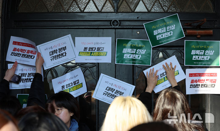 [서울=뉴시스] 이영환 기자 = 이화여자대학교 학생들이 지난 17일 오후 서울 서대문구 이화여자대학교 정문에서 등록금 인상 반대하는 이화인 3239인 서명 전달 기자회견을 마친 후 본관으로 행진해 문이 닫혀 있자 피켓을 붙이고 있다. 2025.01.19. 20hwan@newsis.com