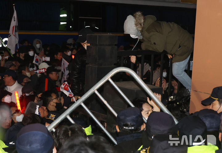 [서울=뉴시스] 김근수 기자 = 내란 우두머리 혐의로 체포된 윤석열 대통령의 구속 전 피의자 심문(영장실질심사)가 열린 18일 서울 마포구 서울서부지방법원에서 시위자들이 담을 넘고 있다. (공동취재) 2025.01.18. photo@newsis.com