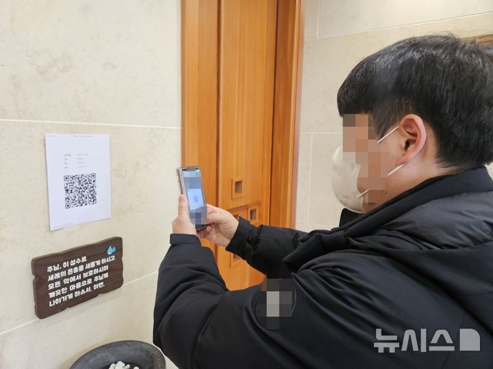 [음성=뉴시스] 19일 충북 음성군 맹동면 두촌성당에서 한 젊은 신자가 QR코드를 이용해 헌금을 하고 있다. 2025.1.19. hugahn@newsis.com