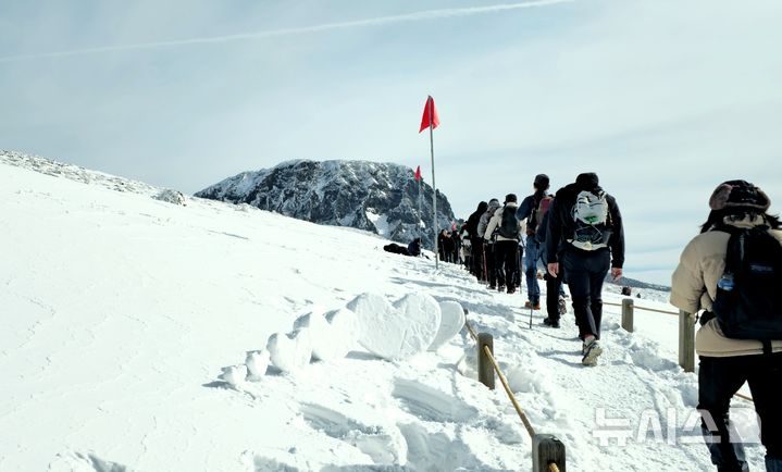 [제주=뉴시스] 18일 오전 한라산 백록담 분화구에 상고대가 피었다. 거대한 분화구 암벽에 상고대가 생기면서 다른 산에서 보기 힘든 독특한 경관을 연출했다. 풍화와 침식작용으로 생긴 화구벽 굴곡 지형에 서리나 물방울이 얼어붙으면서 생긴 백록담 상고대 장관을 향해 등산객들이 걸어가고 있다. 2025.01.19. ijy788@newsis.com