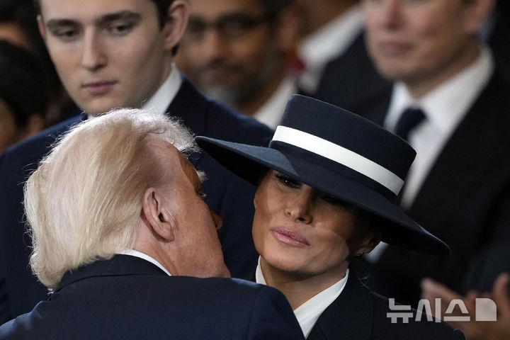 [워싱턴=AP/뉴시스] 도널드 트럼프 미국 대통령 당선인이 20일(현지 시간) 본인의 제47대 대통령 취임식이 열리는 미 연방의회 의사당 로툰다 홀에 입장해 앞서 입장한 부인 멜라니아 여사에게 입 맞추고 있다. 2025.01.21.