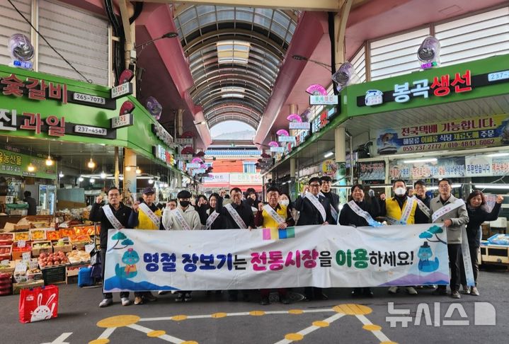 [창원=뉴시스]22일 경남 창원례시 봉곡민속체험시장에서 진행된 전통시장 이용 캠페인에 참여한 경남중기청, 중진공 경남지역본부, 소상공인시장진흥공단 창원센터, 창원시상인연합회 임직원 등이 기념촬영하고 있다.(사진=경남중기청 제공) 2025.01.22.photo@newsis.com