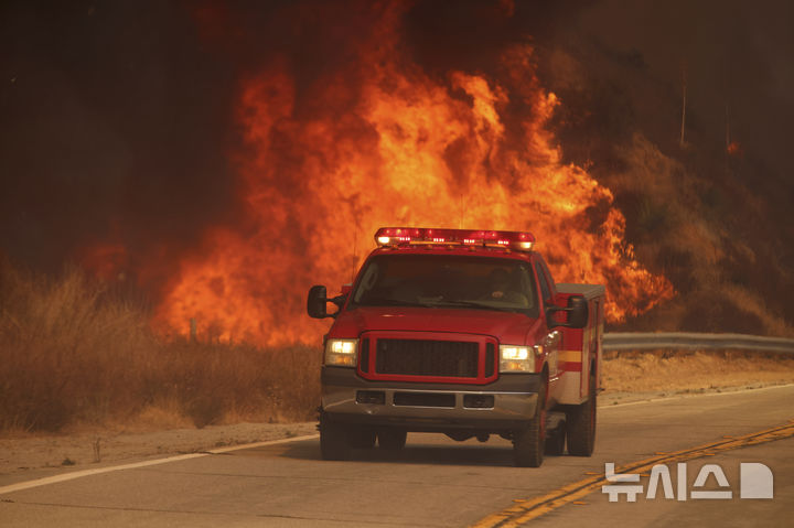 [캐스테이크=AP/뉴시스] 1월 22일 미 캘리포니아주 로스앤젤레스 외곽 캐스테이크 호수 인근에서 '휴즈 파이어'(Hughes Fire) 산불이 발생해 소방차가 불길을 지나 출동하고 있다. 2025.06.30.