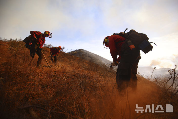[캘리포니아주=AP/뉴시스] 22일(현지 시간) 미국 캘리포니아주 로스앤젤레스 캐스테익 인근에서 '휴즈 산불'이 발생해 소방대원들이 화재 진압을 하고 있다. 2025.01.23.