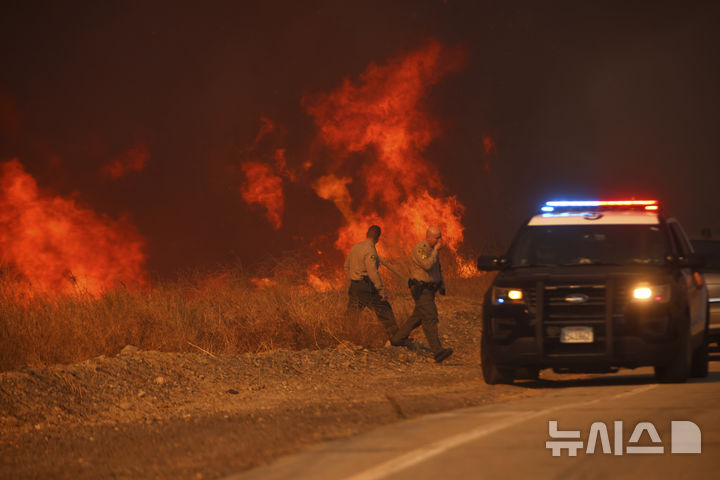 [캘리포니아주=AP/뉴시스] 22일(현지 시간) 미국 캘리포니아주 로스앤젤레스 캐스테익 인근에서 '휴즈 산불'이 발생해 경찰들이 현장을 살펴 본 뒤 이동하고 있다. 2025.01.23.