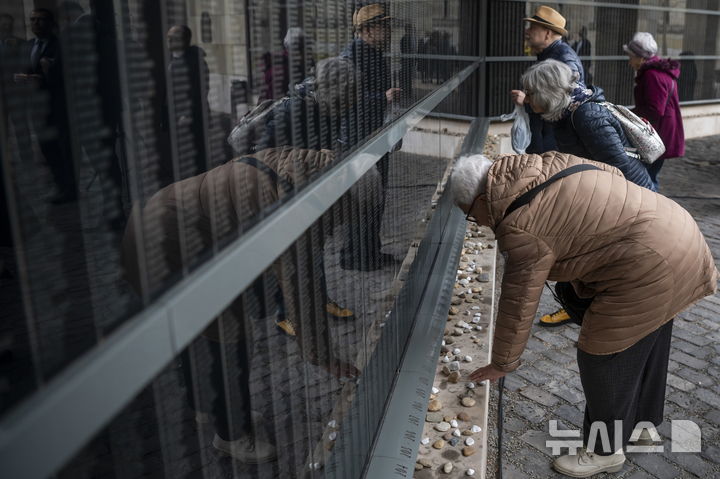[부다페스트=AP/뉴시스] 27일(현지 시간) 국제 홀로코스트 희생자 추모의 날을 맞아 헝가리 부다페스트 홀로코스트 메모리얼 센터에서 방문객들이 희생자들의 이름이 새겨진 추모의 벽을 찾아 추모하고 있다. 2025.01.28.