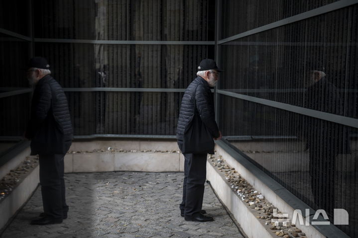 [부다페스트=AP/뉴시스] 27일(현지 시간) 국제 홀로코스트 희생자 추모의 날을 맞아 헝가리 부다페스트 홀로코스트 메모리얼 센터에서 한 남성이 희생자들의 이름이 새겨진 추모의 벽을 찾아 추모하고 있다. 2025.01.28.