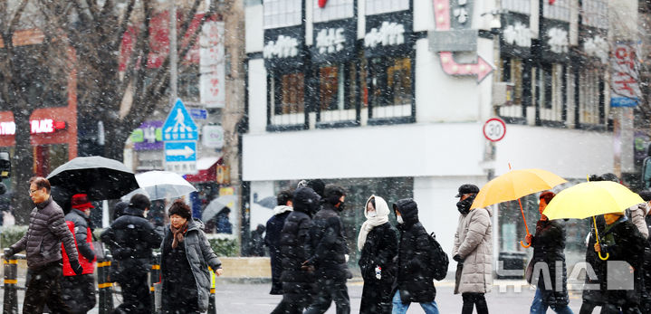 [서울=뉴시스] 전신 기자 = 27일 서울 세종대로사거리에서 시민들이 눈을 맞으며 횡단보도를 건너고 있다. 2025.01.27. photo1006@newsis.com