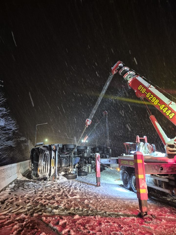 [대전=뉴시스]공주소방서가 28일 오전 3시 11분께 충남 공주시 유구읍 당진∼대전고속도로 대전 방향 승지교에서 빙판에 넘어진 LPG 탱크로리를 중장비를 동원해 치우고 있다. (사진=공주소방서 제공). 2025. 01. 28 photo@newsis.com *재판매 및 DB 금지