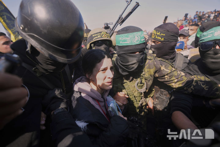 [AP/뉴시스] 이스라엘 민간인 여성인질 아르벨 예후드가 30일 칸유니스에서 복면 하마스에 의해 국제적십자 측에 인계되고 있다. 여군 출신인 예후드는 당초 25일 여군 현역 4명과 함께 석방될 예정이었다. 