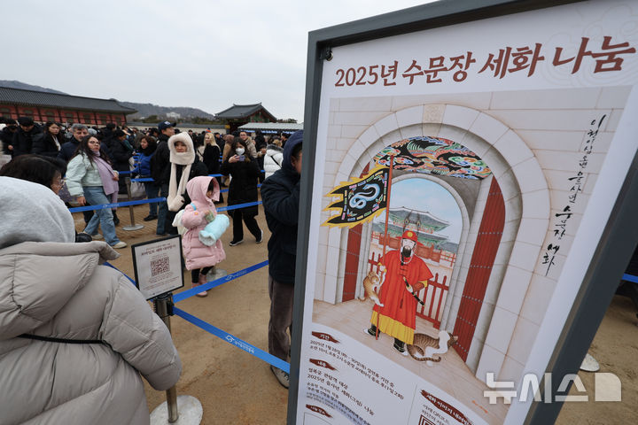 [서울=뉴시스] 김명원 기자 = 설 연휴 마지막날인 30일 서울 종로구 경복궁 홍례문 광장에서 시민들과 관광객들이 푸른 뱀이 그려진 깃발을 잡고 선 수문장과 고양이를 그린 세화(歲畵)를 받고 있다. 세화는 질병이나 재난을 예방하고 한 해 동안 행운이 깃들기를 바라는 마음이 담긴 그림으로 조선시대에 새해를 맞이하여 왕이 신하들에게 그림을 하사하던 것에서 유래해 민간 풍습이다. 2025.01.30. kmx1105@newsis.com