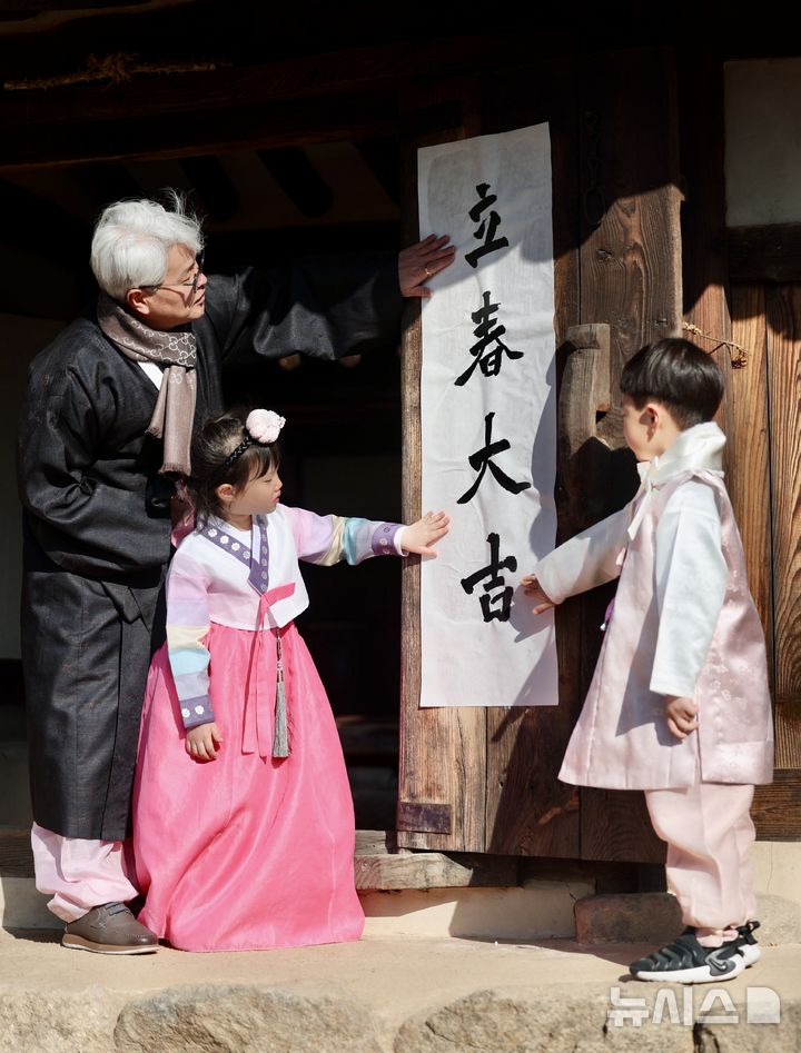 [서울=뉴시스] 김명년 기자 = 절기상 입춘(立春)인 3일 오전 서울 종로구 국립민속박물관 오촌댁 대문에서 서예가와 어린이들이 입춘첩을 붙이고 있다. 2025.02.03. kmn@newsis.com
