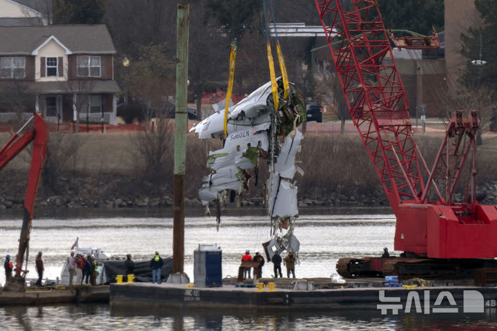 [알링턴=AP/뉴시스] 3일(현지 시간) 미 버지니아주 알링턴의 로널드 레이건 워싱턴 공항 인근 포토맥강에서 구조대가 군용 헬기와 충돌 후 추락한 여객기 잔해를 인양하고 있다. 도널드 트럼프 미 대통령이 이 사고가 다양성 촉진 정책에 따라 고용된 연방항공청(FAA) 당국자들의 무능이 책임이라는 주장을 폈다. 2025.02.04.