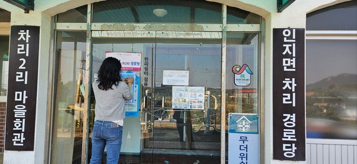 [서산=뉴시스] 지난해 10월 무더위와 한파 쉼터로도 쓰이는 서산시 인지면 차리경로당 현관 유리문에 한 공무원이 홍보물을 붙이고 있다. (사진=서산시 제공) 2025.02.04. photo@newsis.com *재판매 및 DB 금지