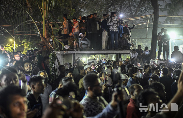[다카=AP/뉴시스]&nbsp; 2월 6일(현지 시간) 방글라데시 다카 단몬디 지역에서 시위대가 중장비로 셰이크 하시나 전 총리의 부친이자 '건국의 아버지'인 무지부르 라만의 저택을 철거하는 모습을 지켜보고 있다. 인도에 망명 중인 하시나 전 총리가 자신이 이끌던 정당 아와미연맹(AL)을 앞세워 정치적 재기를 노리는 행보를 보이자, 그에 반대하는 시위대는 방글라데시 독립의 상징이었던 라만의 저택을 훼손하고 철거하기에 이르렀다. 2025.06.02.