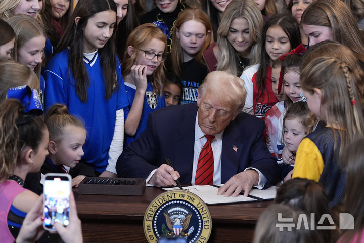 [워싱턴=AP/뉴시스] 도널드 트럼프 미국 대통령이 지난 2월 5일 백악관 이스트룸에서 여학생 선수들이 지켜보는 가운데 성전환 여성 운동선수의 여성·소녀 운동 경기 참가를 금지하는 행정명령에 서명하고 있다. 트럼프 대통령의 명령에 따라 캘리포니아주는 육상 선수권대회에 참가하는 "생물학적 여성"의 관문을 일부 더 넓히겠다고 5월 27일 발표했다. 2025.05.28.