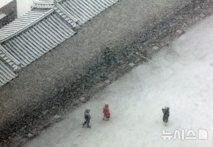 [서울=뉴시스] 배훈식 기자 = 서울 전역에 대설주의보가 내려진 6일 오후 서울 종로구 광화문 담장 앞에서 관광객이 기념사진을 찍고 있다. 2025.02.06. dahora83@newsis.com