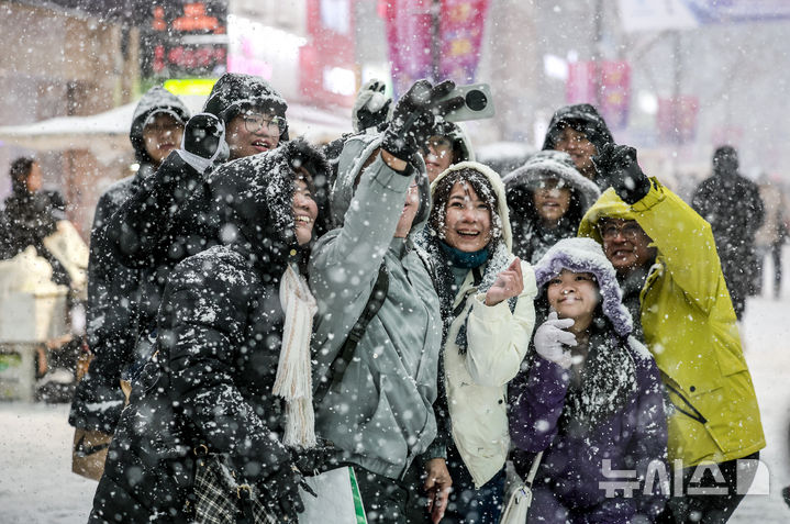 [서울=뉴시스] 정병혁 기자 = 6일 서울 중구 명동을 찾은 여행객들이 눈을 배경으로 사진을 찍고 있다. 2025.02.06. jhope@newsis.com